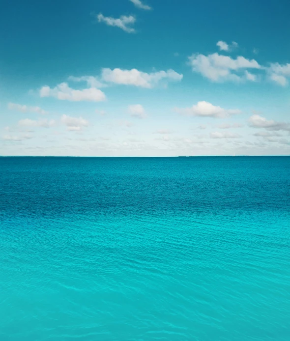 the bright blue ocean with some clouds and light colored water