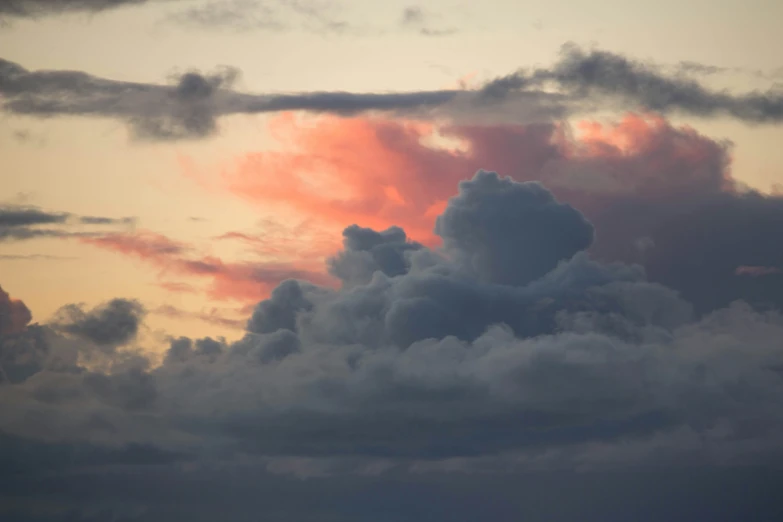 the airplane is flying in the clouds at sunset