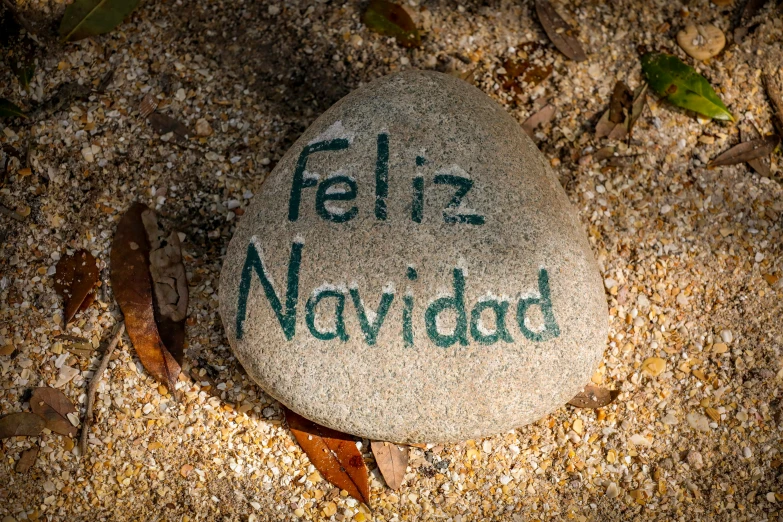 a rock in the sand that reads feliz navidad