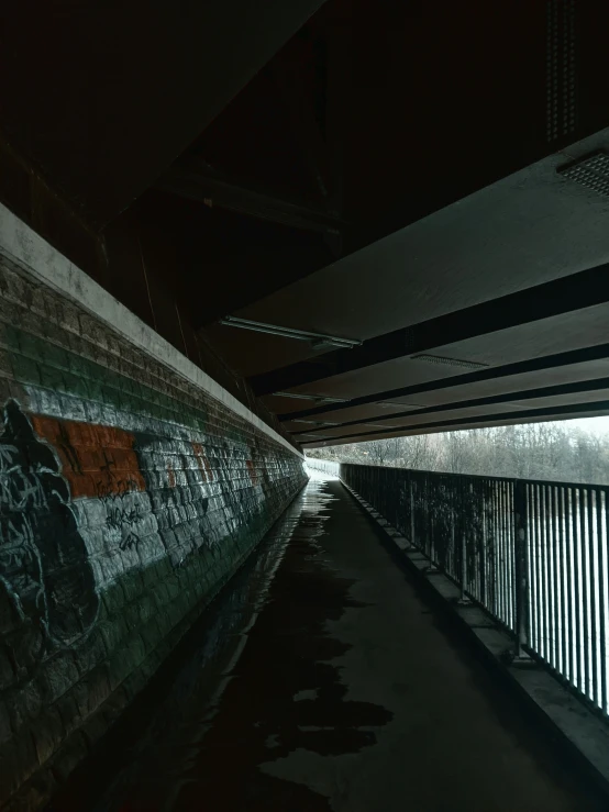 a street with a concrete wall, and an overpass at night