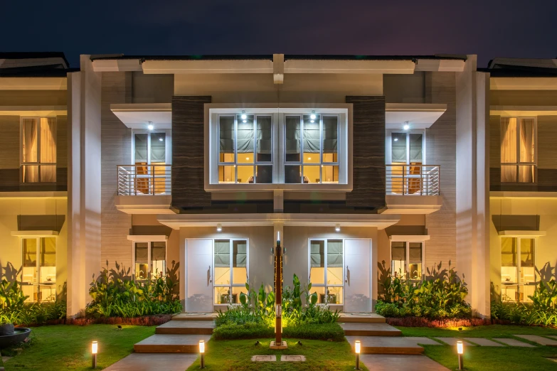 the front entrance to a large, upscale house with a lawn and steps