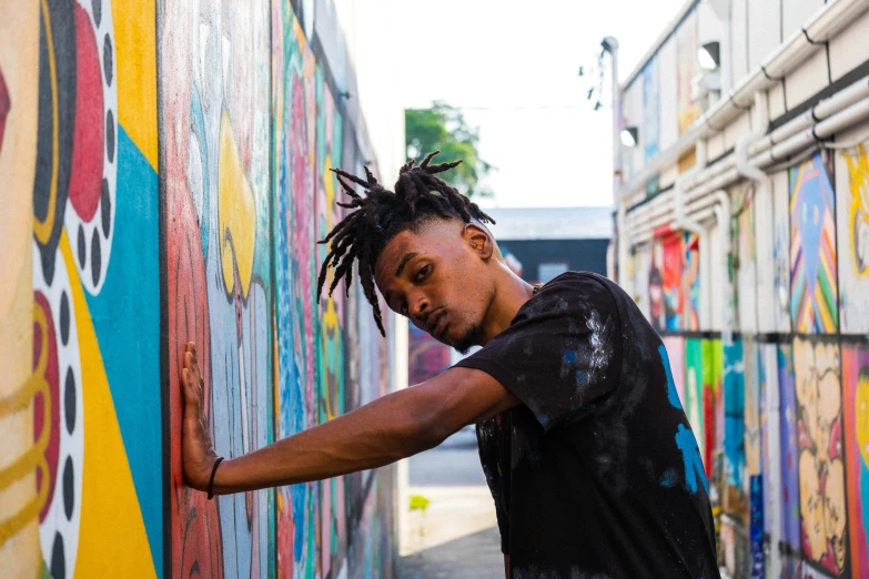 a young man standing in front of a colorful wall