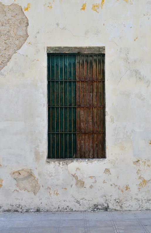 the outside of a white wall with bars around a window