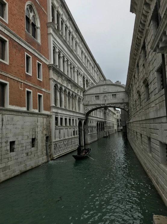 a small boat going down a river by a bridge