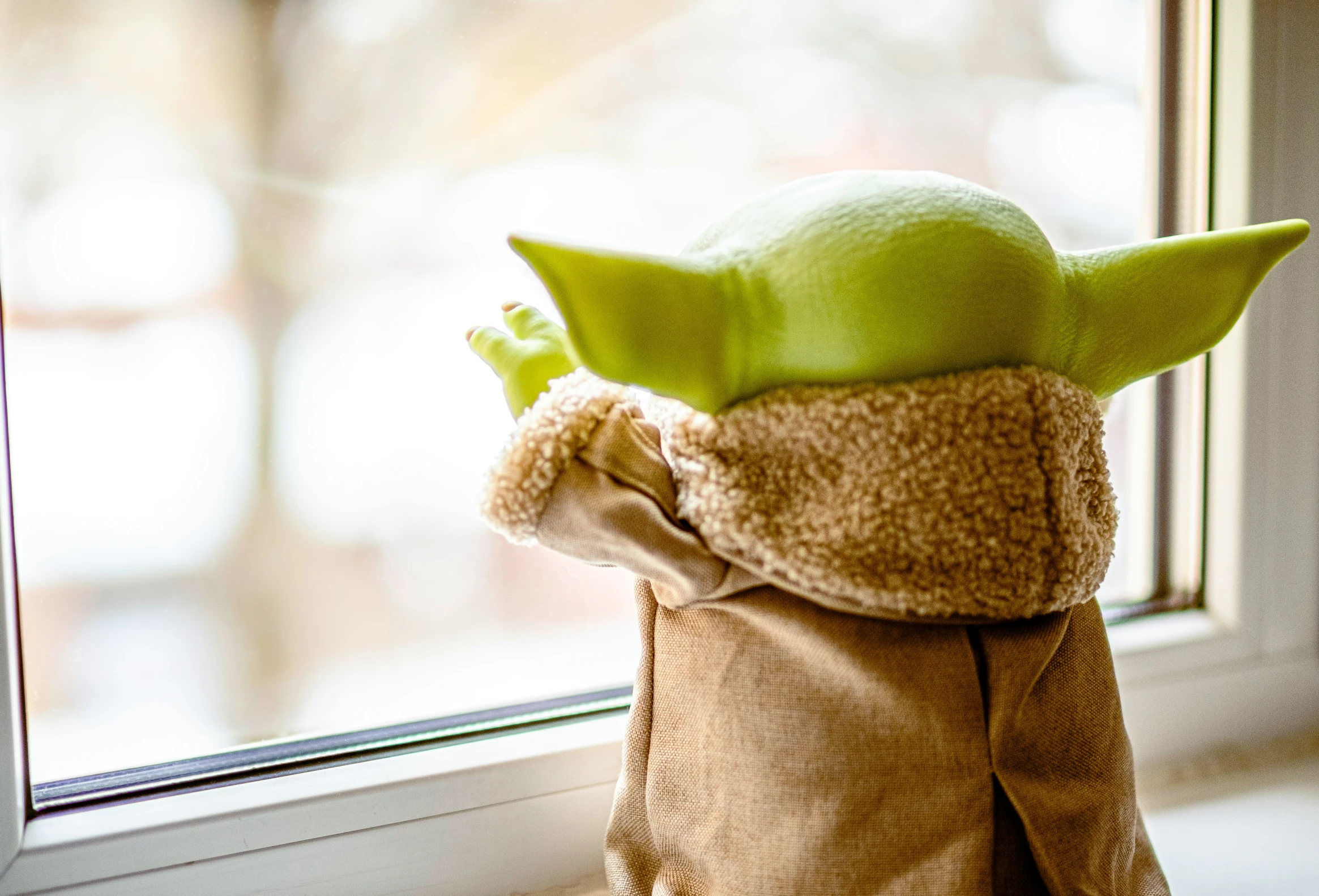 the green doll is next to the window ledge