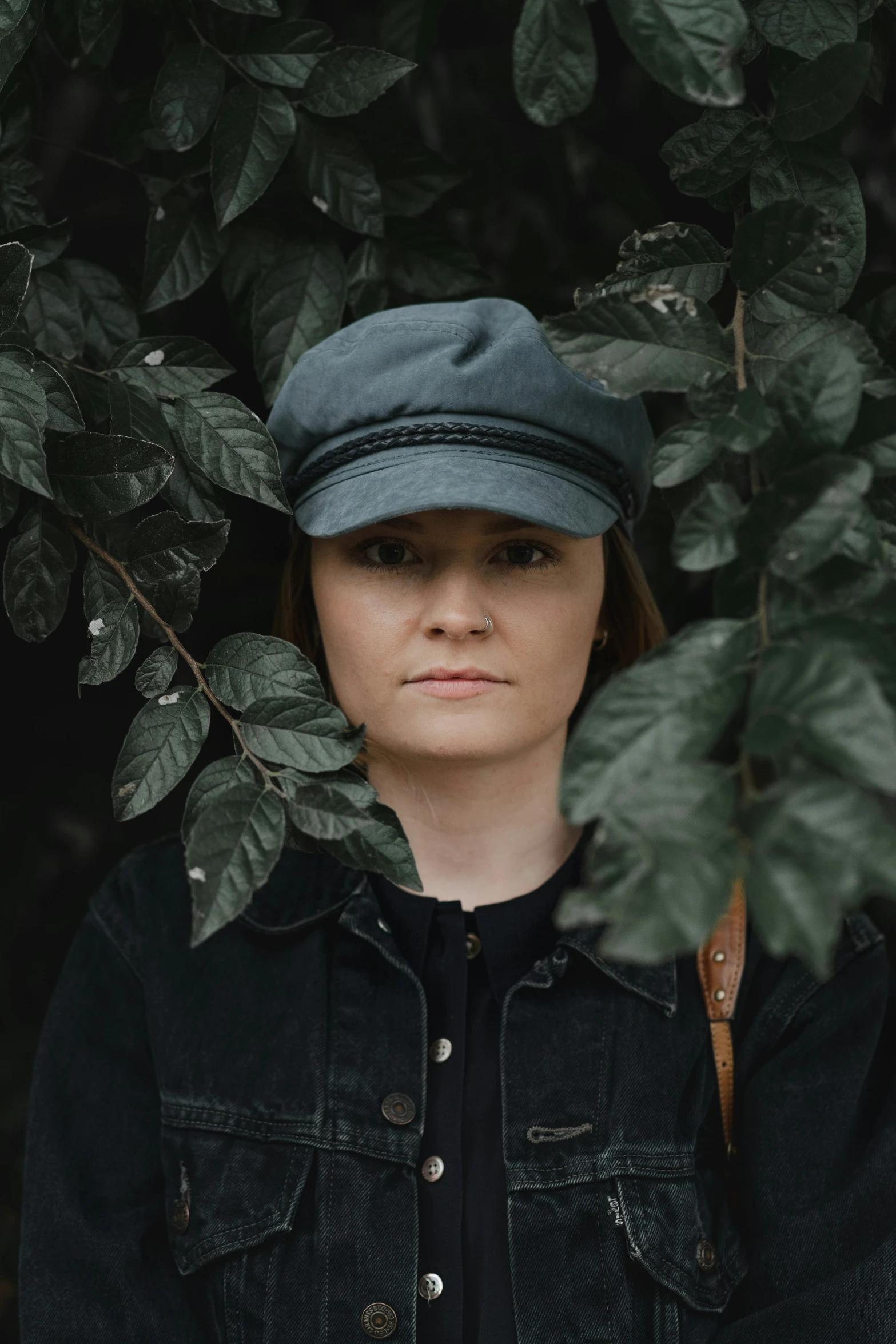 a woman in a denim jacket and green hat poses for a po