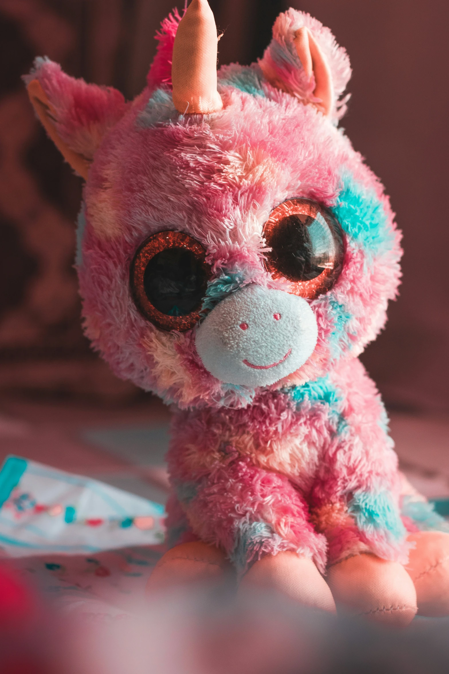 a pink stuffed animal with a unicorn nose and horns