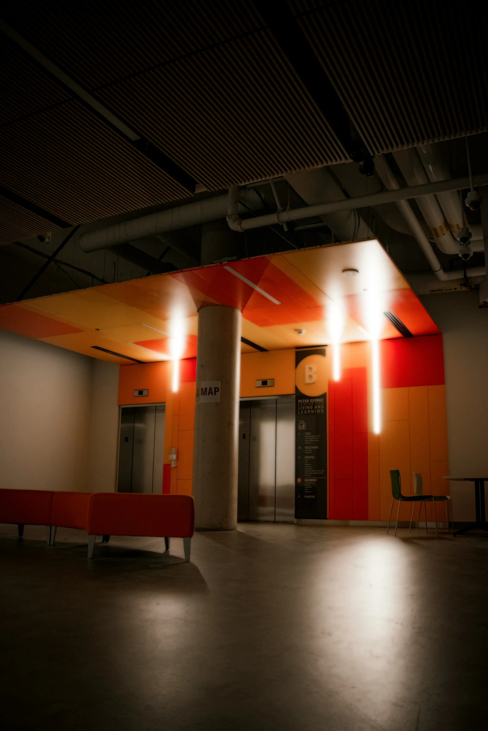 an empty room with concrete floors, an orange wall and a red bench at the front