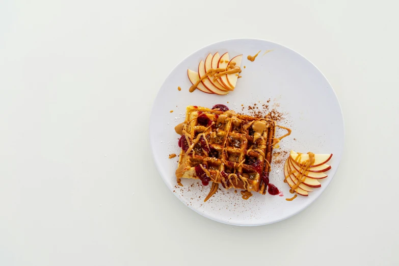 plate with waffle and apple slices with chocolate sauce on top