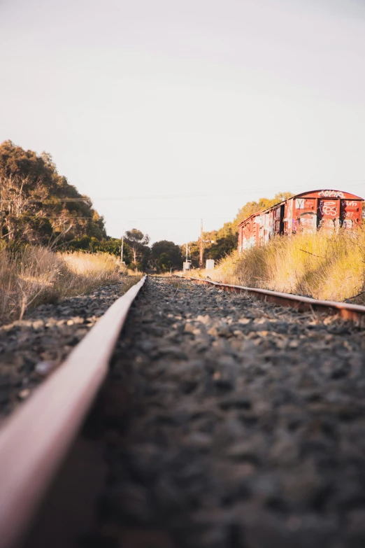 a view down the tracks of a red abandoned train car