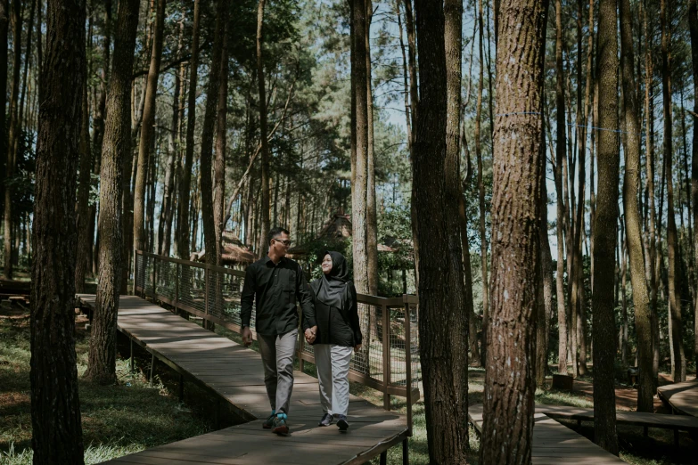 the man and woman are walking through the trees