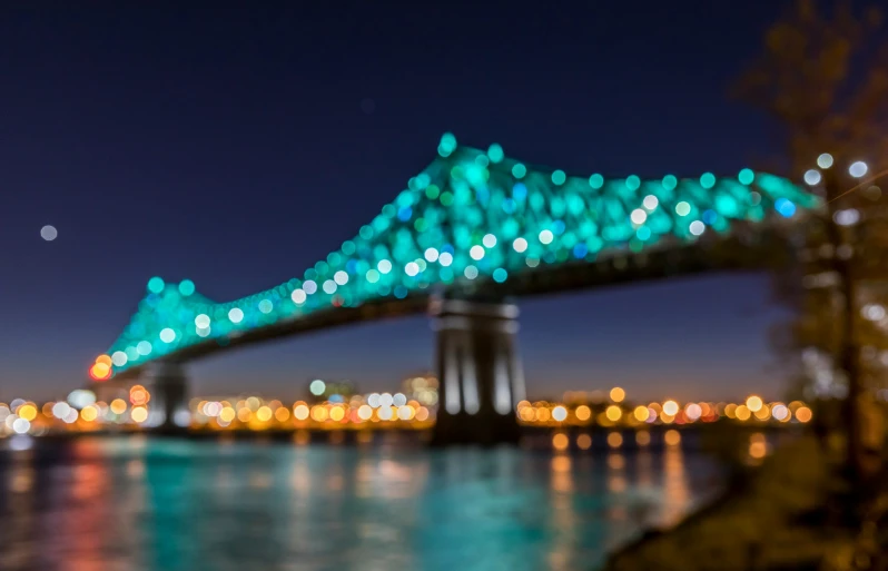 the view of an illuminated blue bridge and river