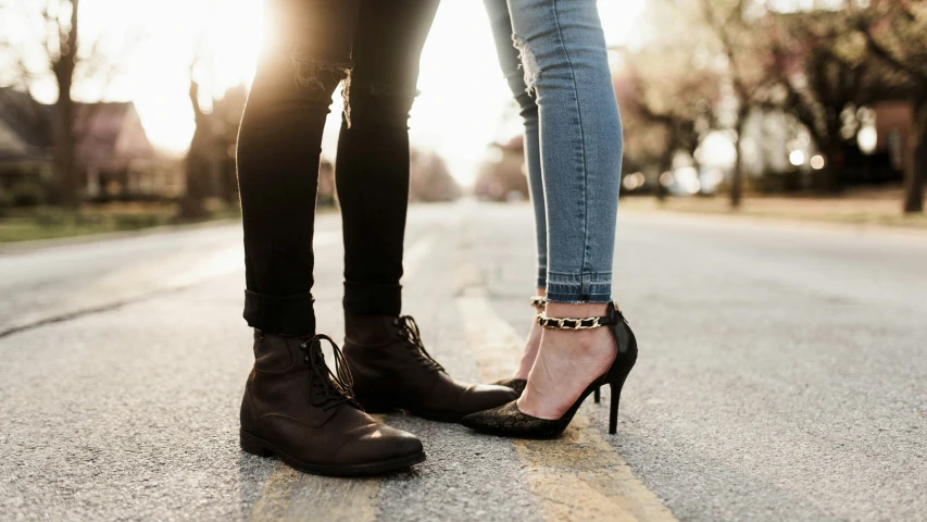 two people standing in the middle of a road wearing high heels