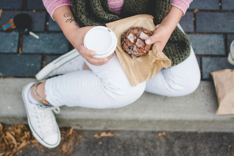 a girl is holding a cup of coffee and some food