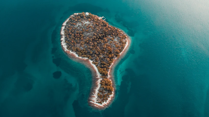 an island floating in the middle of blue water