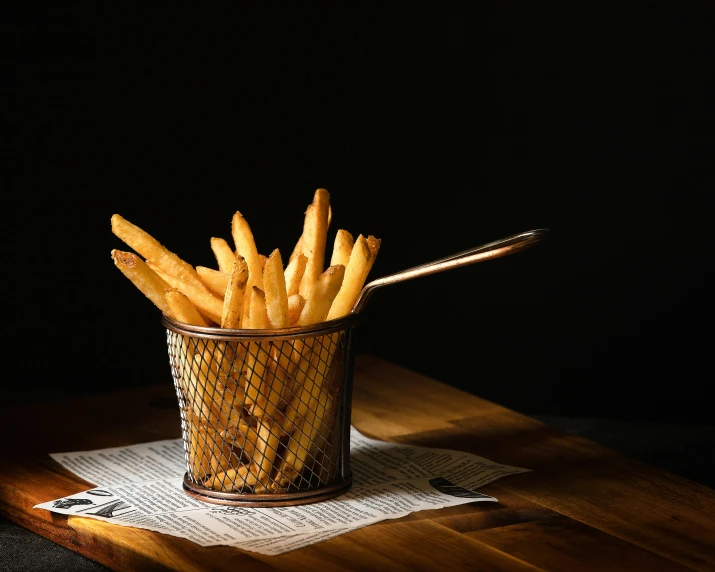 french fries are in a glass on top of a wooden table