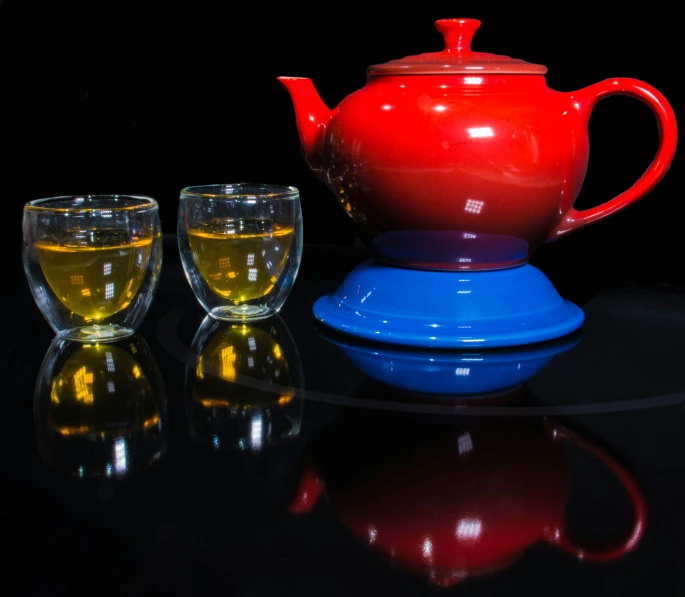 two cups are placed in front of an open teapot