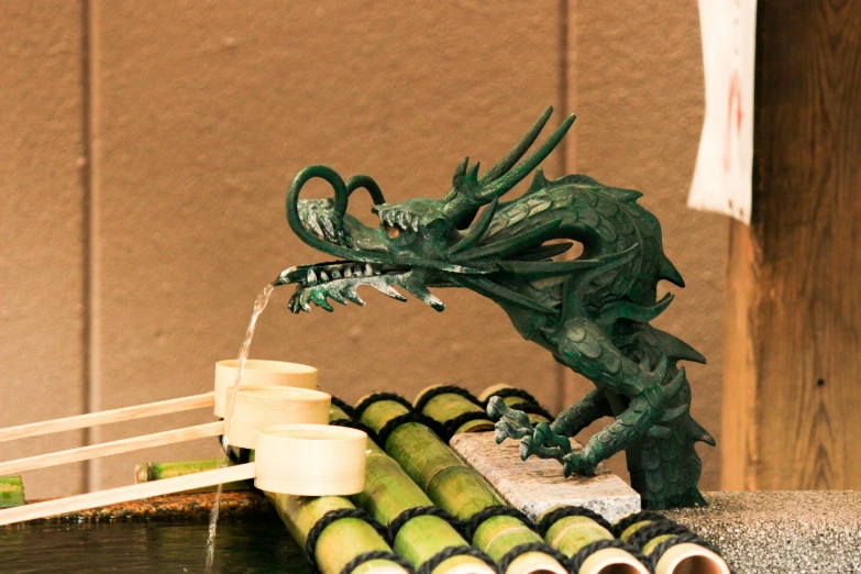 a small green dragon fountain surrounded by bamboo sticks