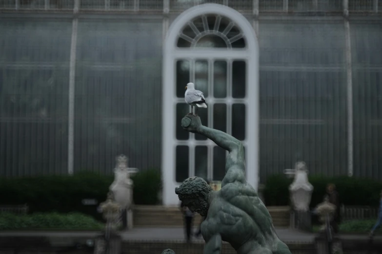 a statue of a man holding a pigeon in front of a large building