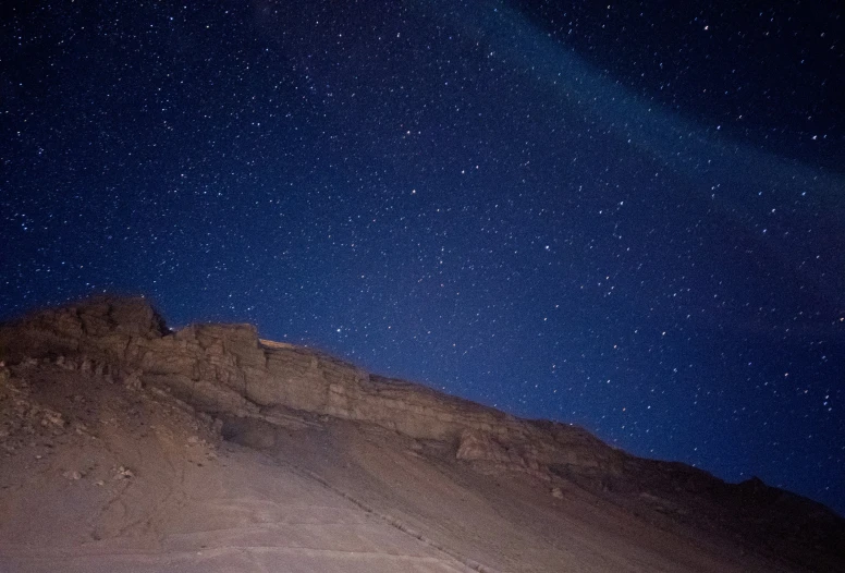 some rocks mountains clouds and stars on a dark night