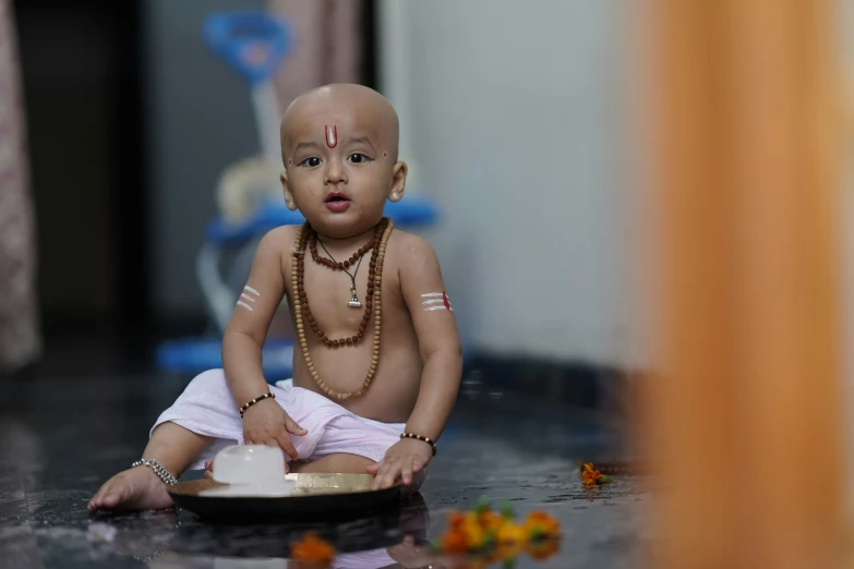 a very small baby sitting on the floor with some beads on