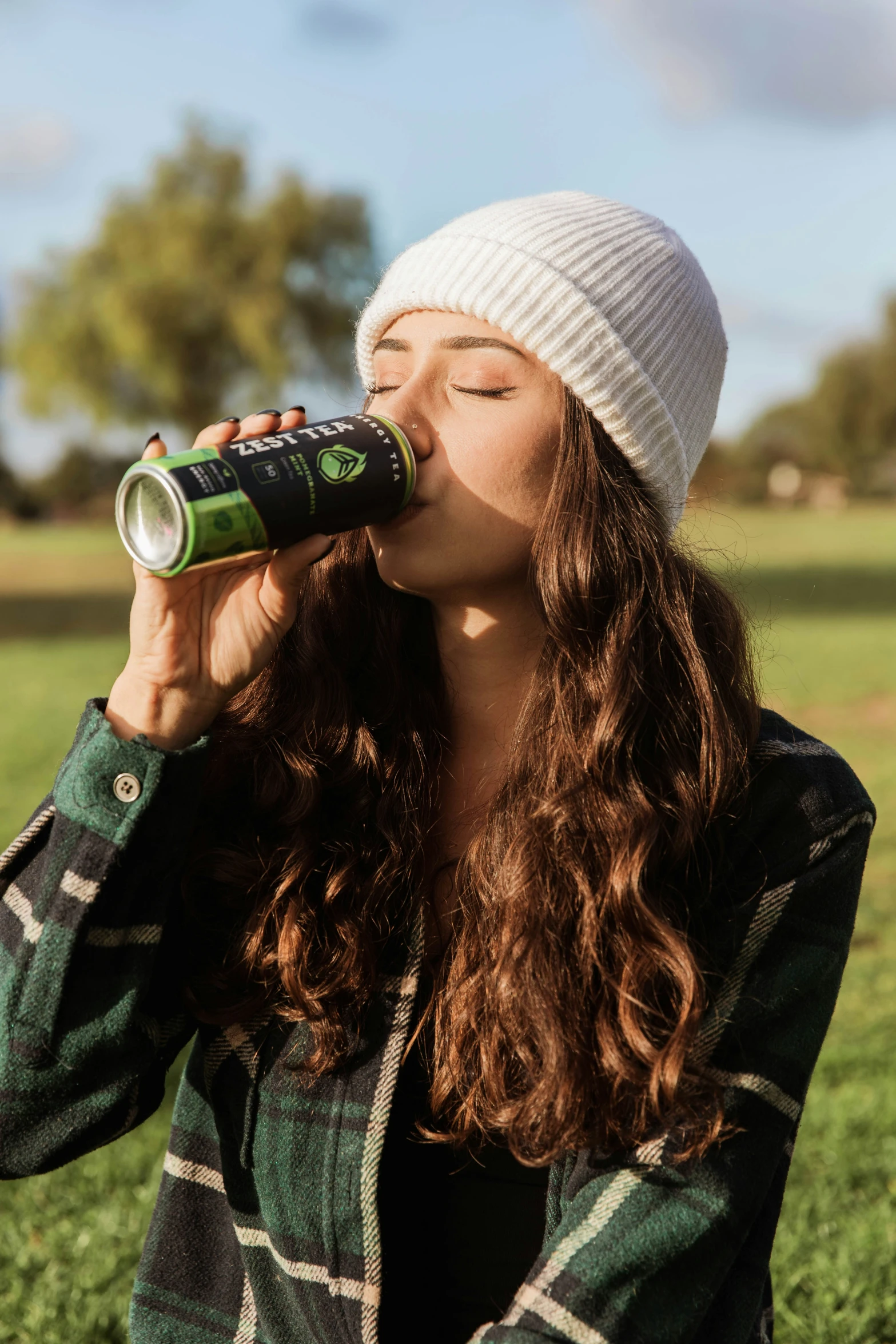 girl drinking coke from a can outdoors in the grass