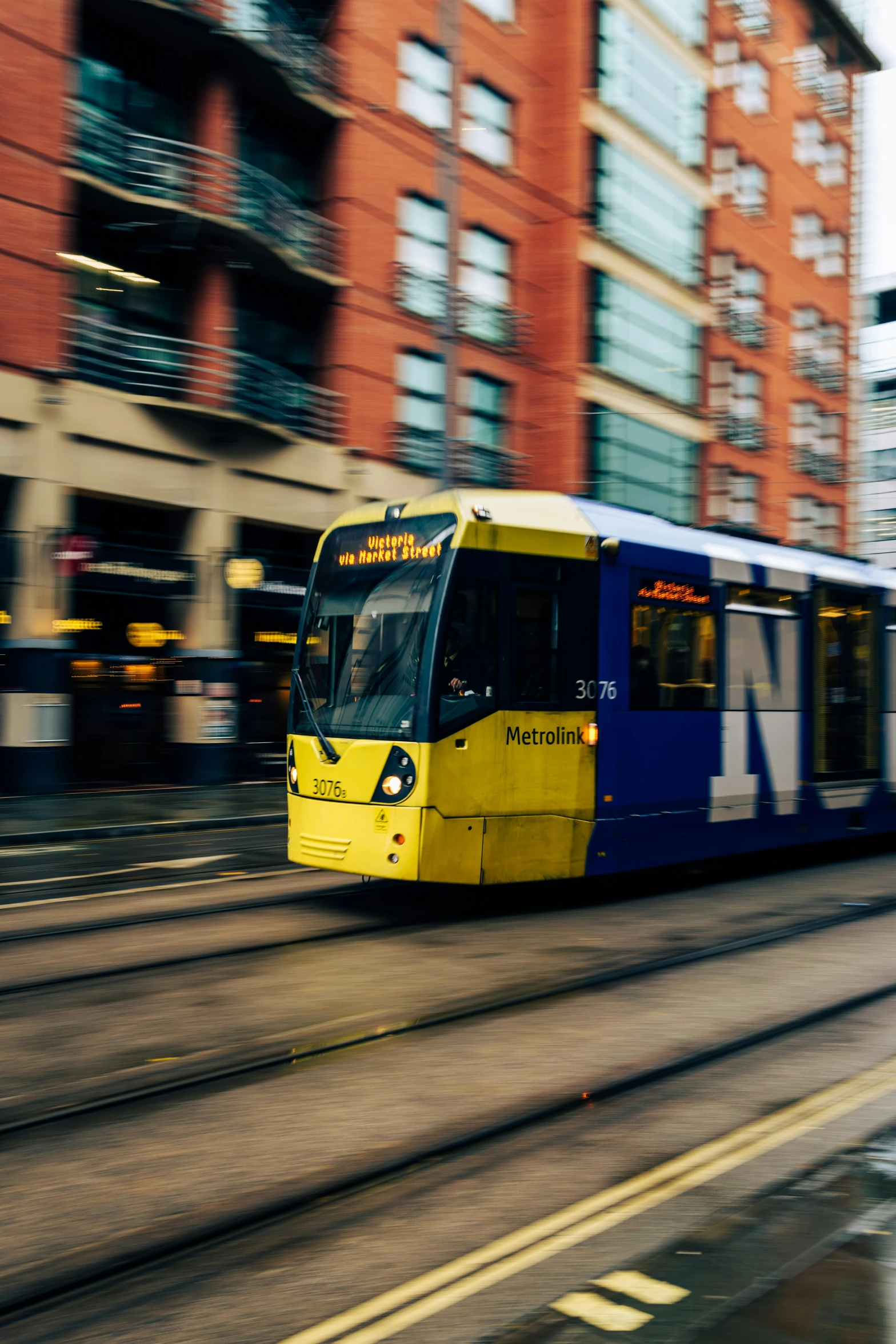 a train driving down a street next to tall buildings