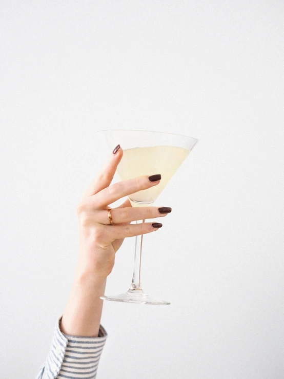 woman's hand holding up small wine glass with a stem