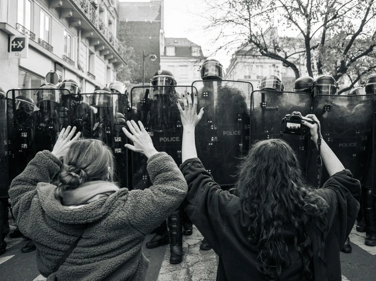 two people hold up their cell phones behind a fence