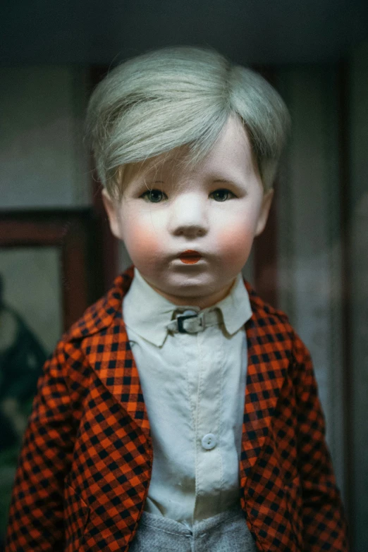 a doll in red and white jacket and grey pants