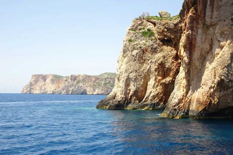 the cliffs of an island near a small ship