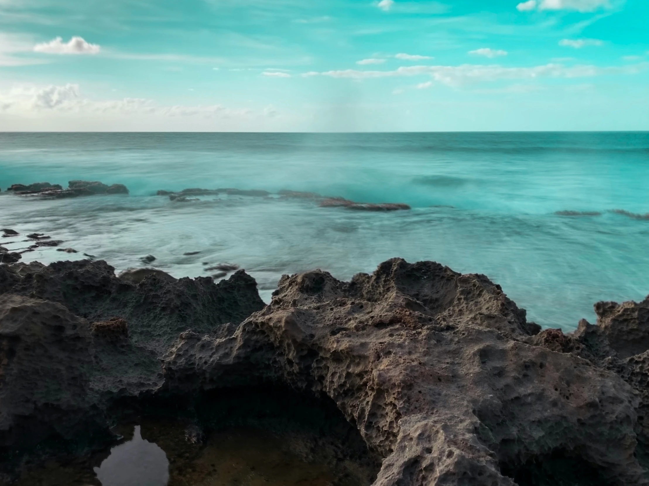 rocky shore with clear blue water and white clouds