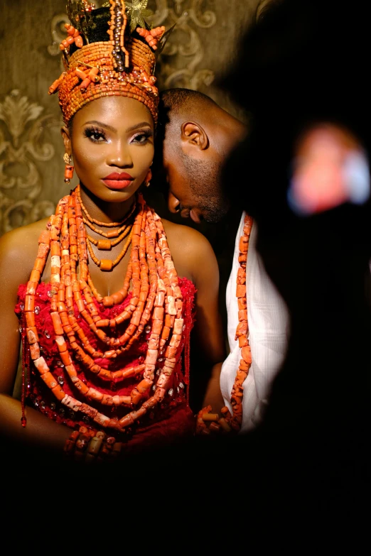 a man in a turban and headdress is standing near a woman with a head piece on her head