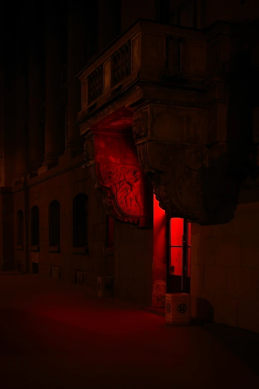 a dark street with a sign and some red light