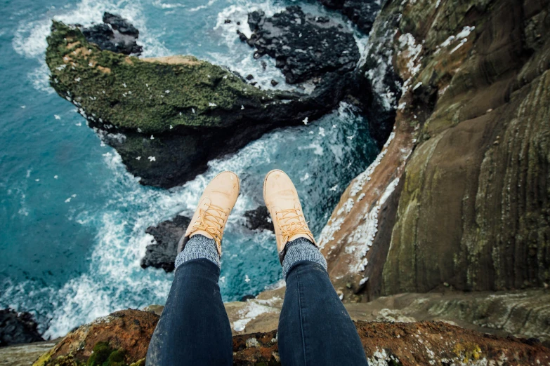 a persons feet in high heels and jeans are overlooking the water