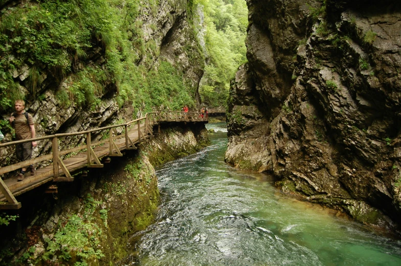 a bridge crossing a river through a narrow canyon