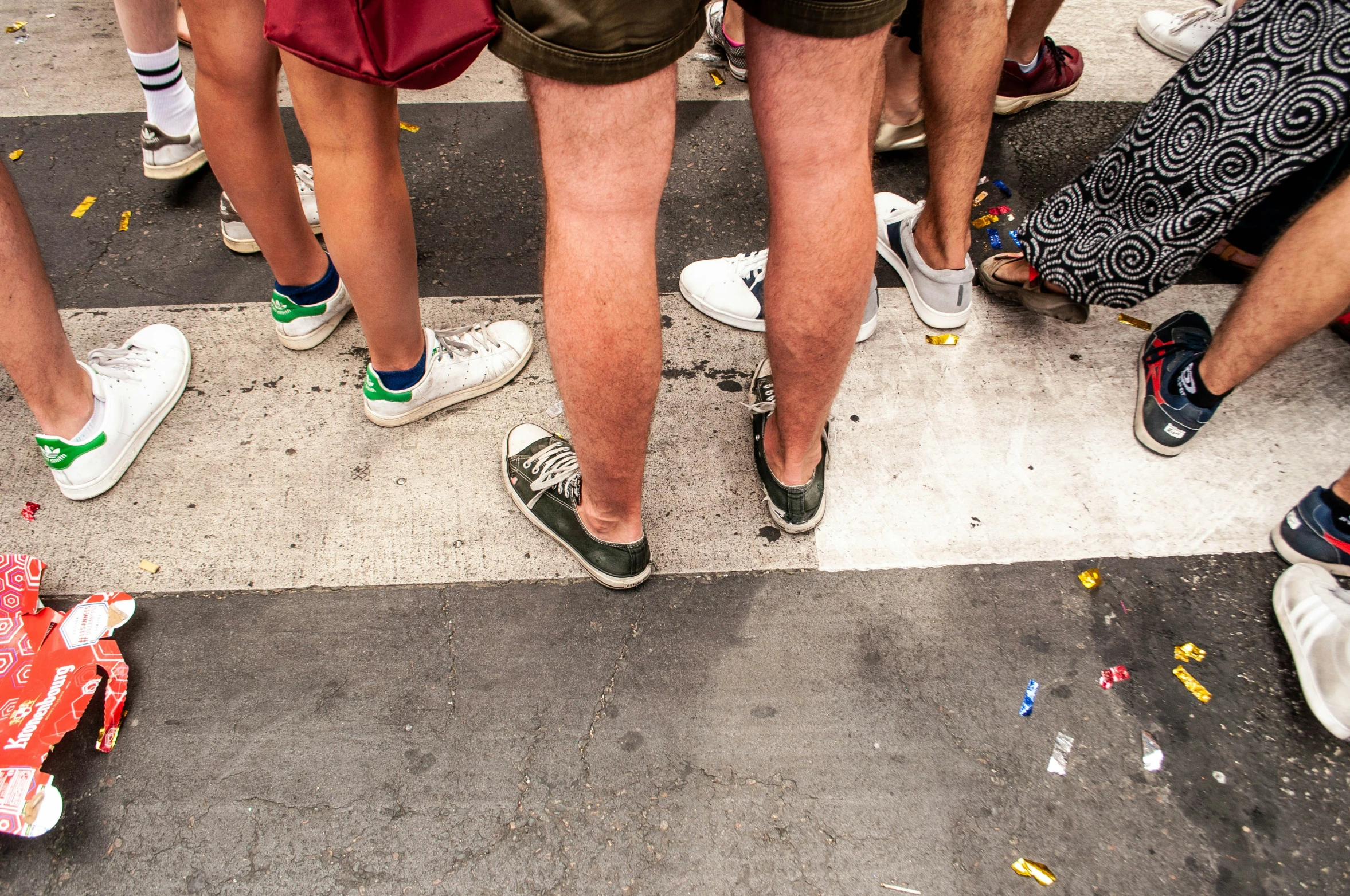 many people are standing on a street with different types of shoes