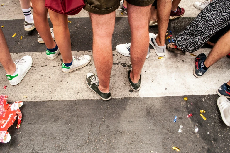 many people are standing on a street with different types of shoes