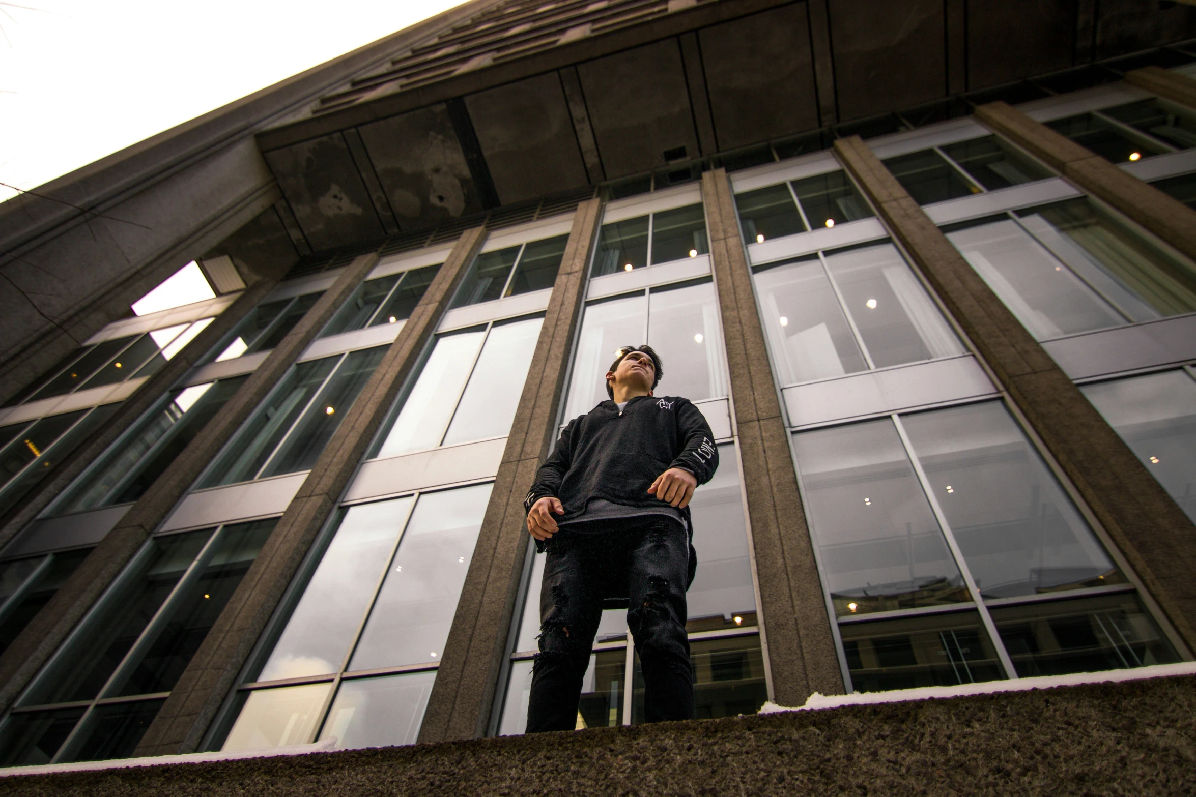 a man is standing on the ledge outside of a building