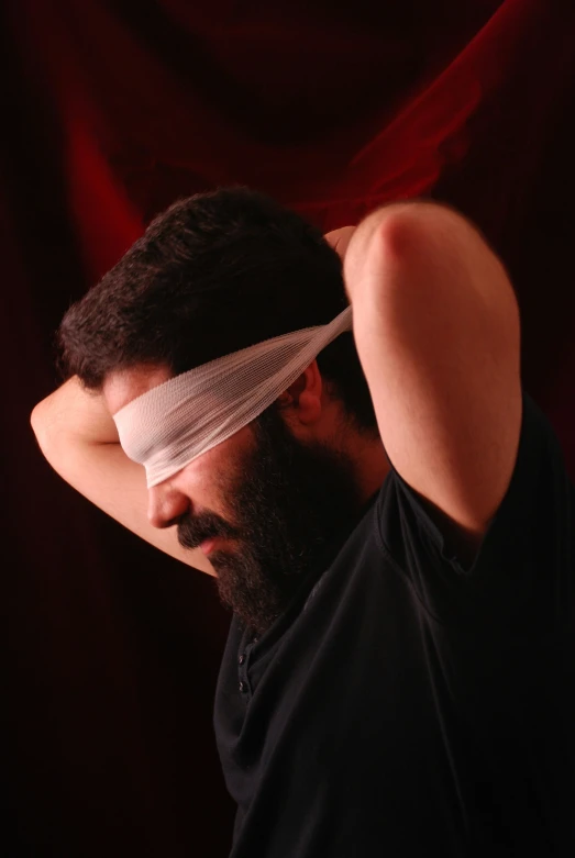 the man with the bandage over his eyes is rubbing his head