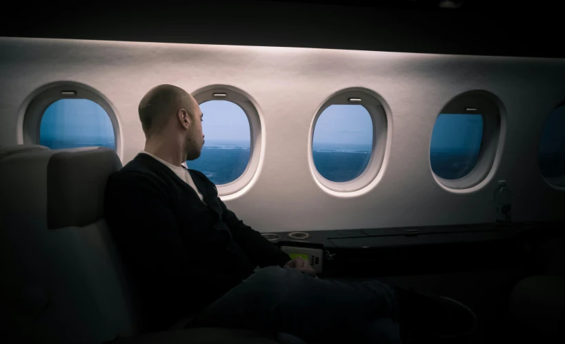 a man sitting on an airplane with out the window