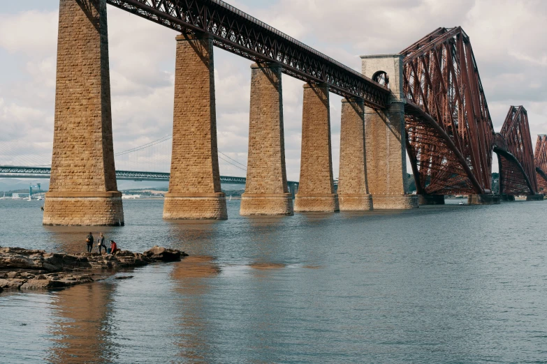 a large bridge over water next to a stone formation