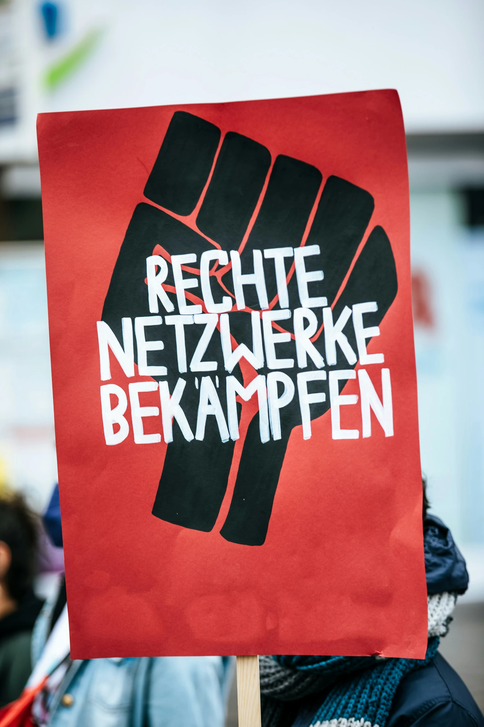 a man holding up a sign that reads recite netzwerke bekampfen