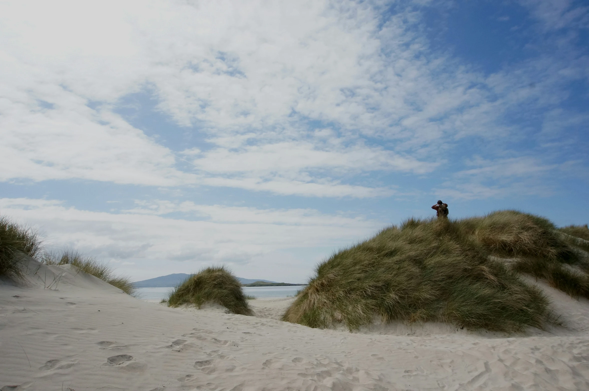 a man standing on top of a beach surrounded by sand dunes