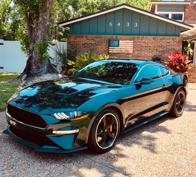 a black and blue mustang parked in front of a house
