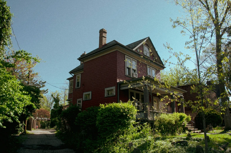 a large red brick house next to some bushes