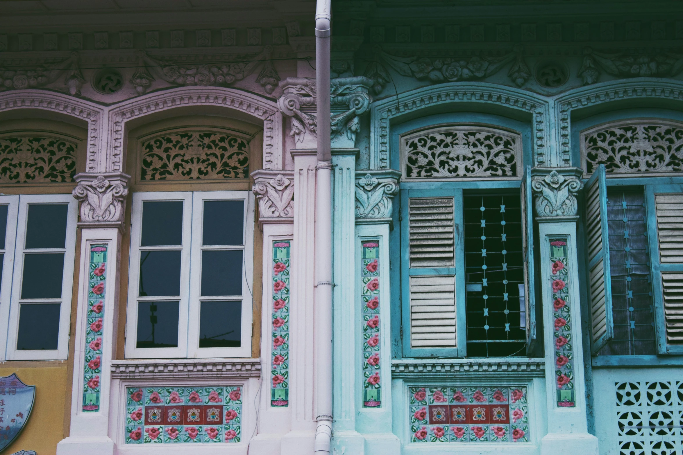 two windows with decorative wooden shutters with flowers on them