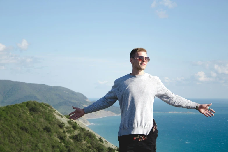 a man with arms wide open on the side of a mountain