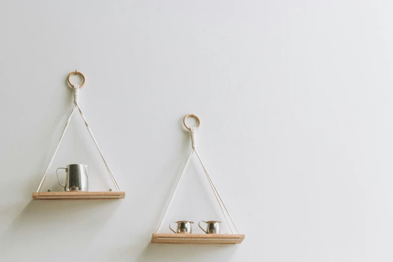 two teacups are hanging from the hooks on the wall