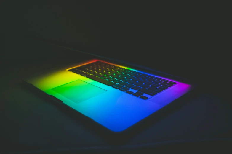 a glowing laptop keyboard illuminated in rainbow light